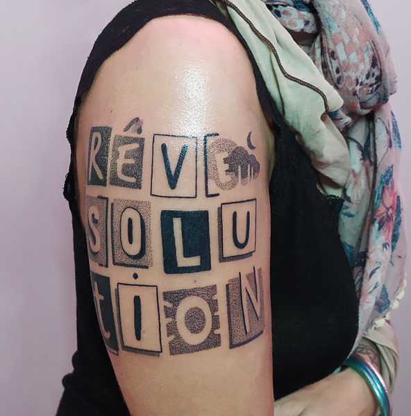 Ce que je tatoue : photographie d'un tatouage texte "rêve", "solution" et "révolution"