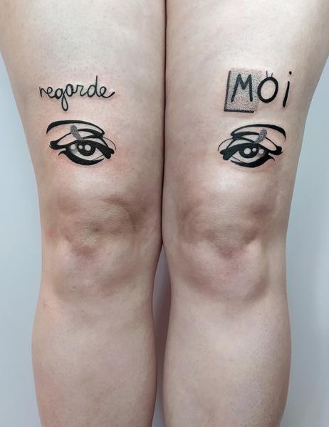Ce que je tatoue : photographie d'un tatouage texte "regarde-moi" avec deux yeux